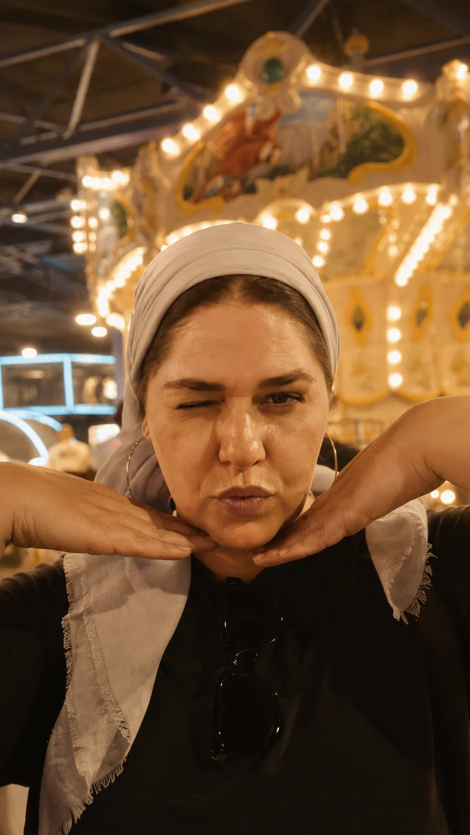 הילה אזרד עושה פרצוף מצחיק מול קרוסלה מוארת